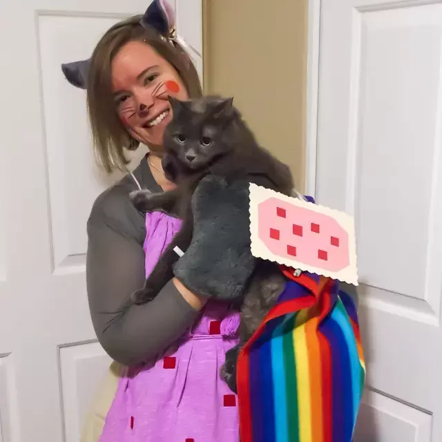 Brianna in a Nyan Cat costume, holding her grey cat who is also sporting a Nyan Cat costume | Kitten KaZoedle